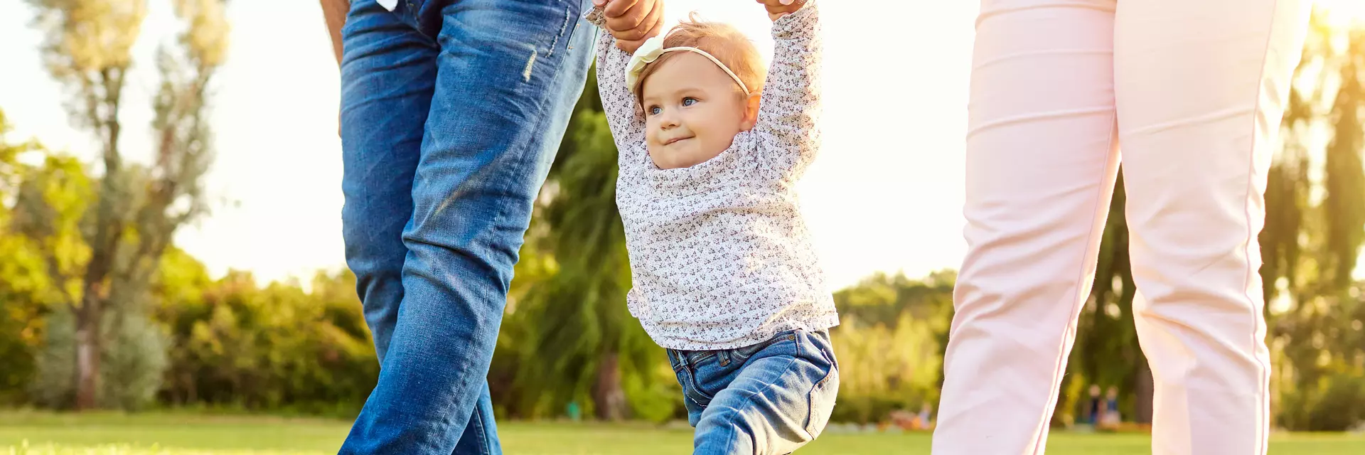 Mama Papa und Kleinkind spazieren über die Wiese