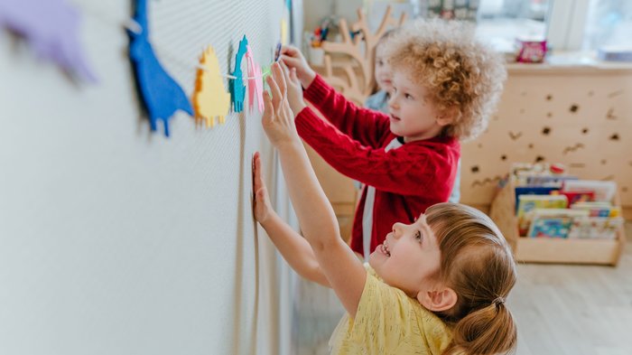 Zwei Vorschulkinder spielen in der Kinderbetreuung mit Dinosaurierschablonen