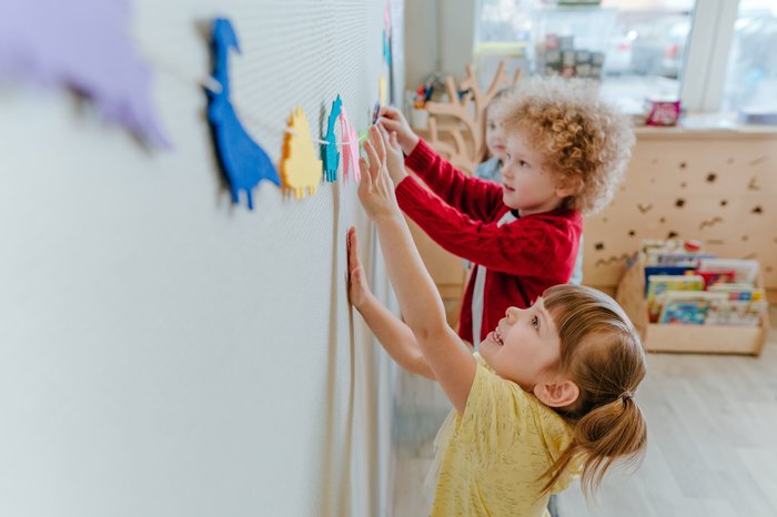 Zwei Vorschulkinder spielen in der Kinderbetreuung mit Dinosaurierschablonen