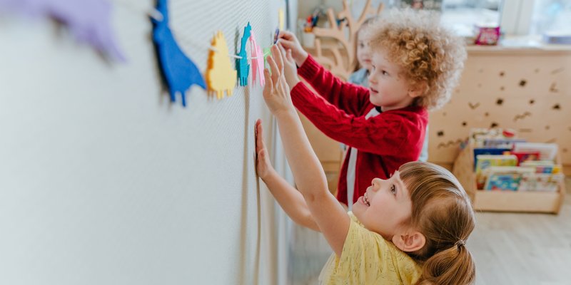 Zwei Vorschulkinder spielen in der Kinderbetreuung mit Dinosaurierschablonen