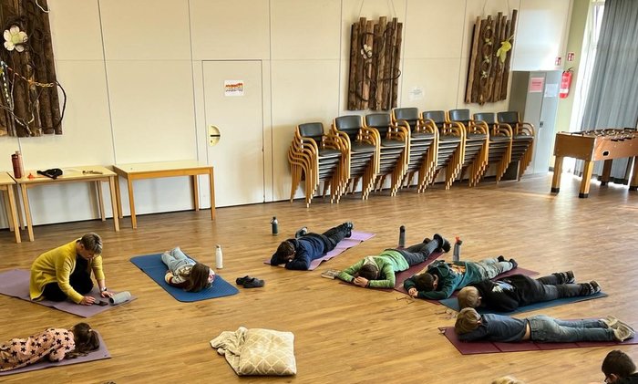 Kinder entspannen sich auf Yogamatten im Raum Menden auf Gut Holmecke