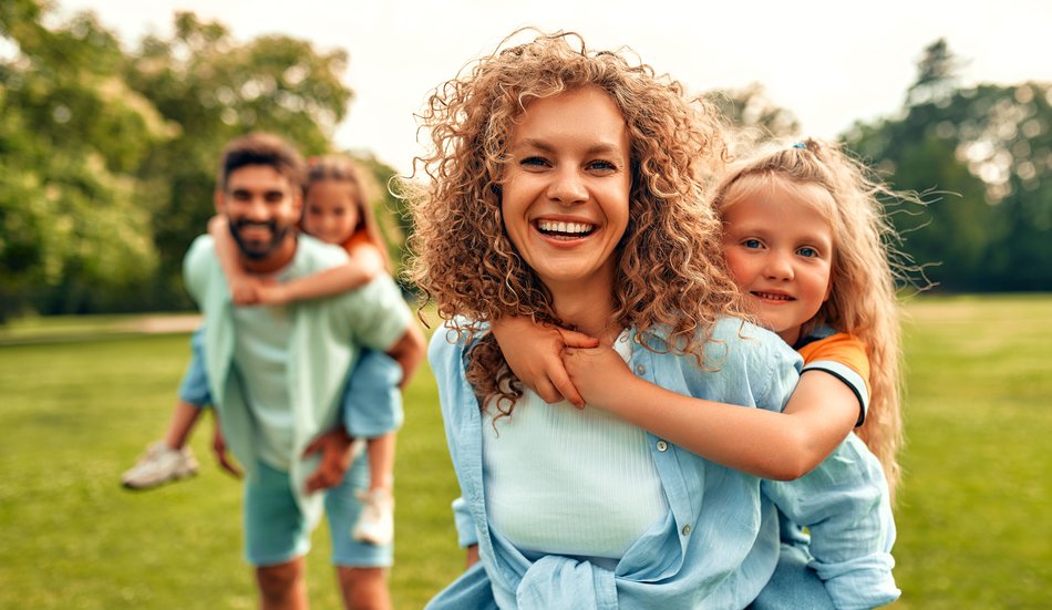 Lachende Eltern mit fröhlichen Kindern auf dem Rücken